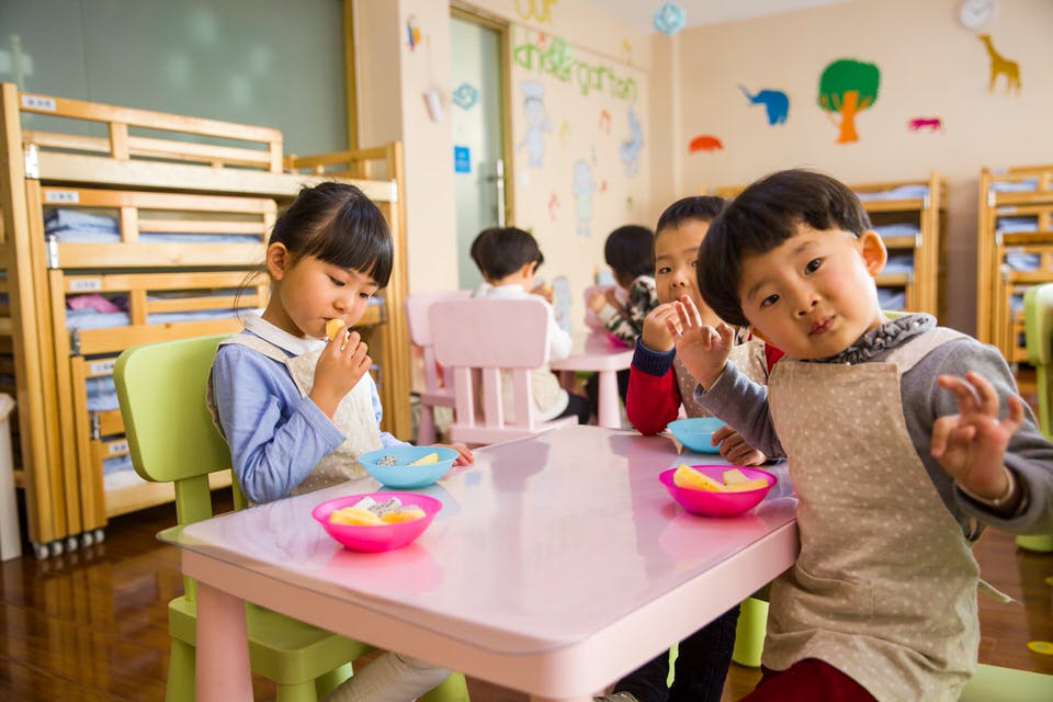 3 preschool children sitting at a table eating a snack